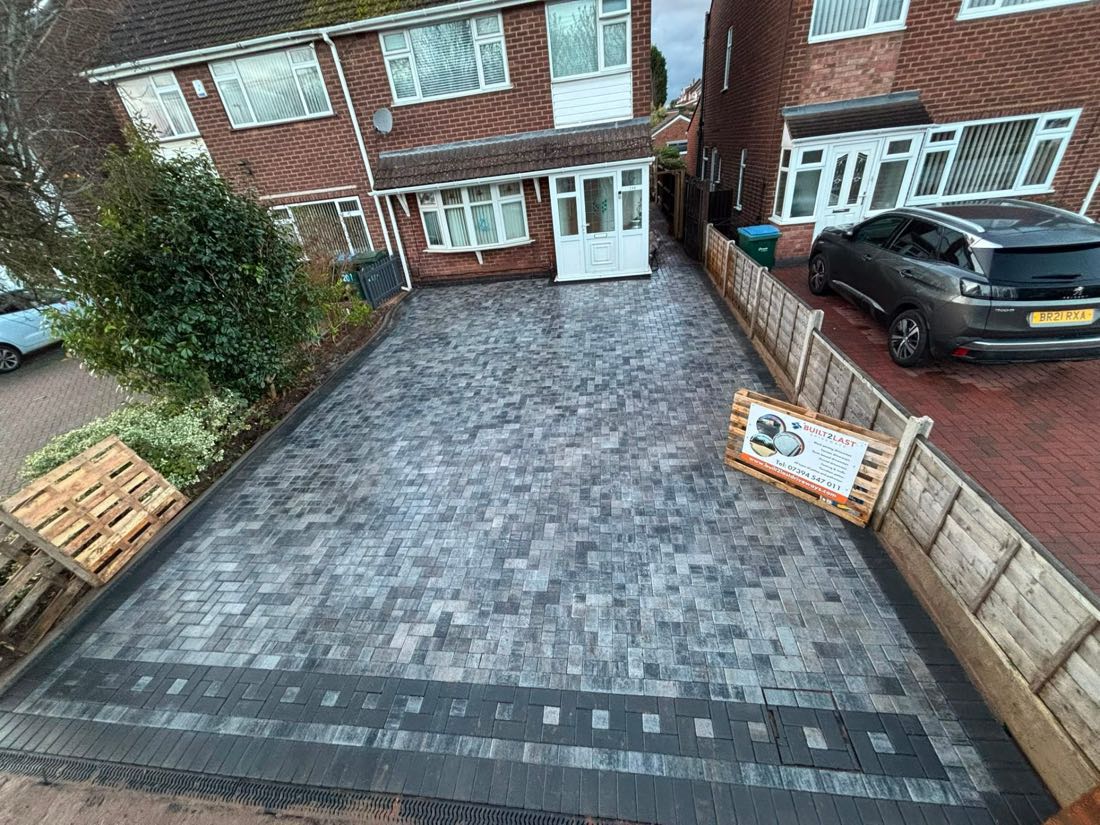 Charcoal block paved driveway with decorative border and channel drainage